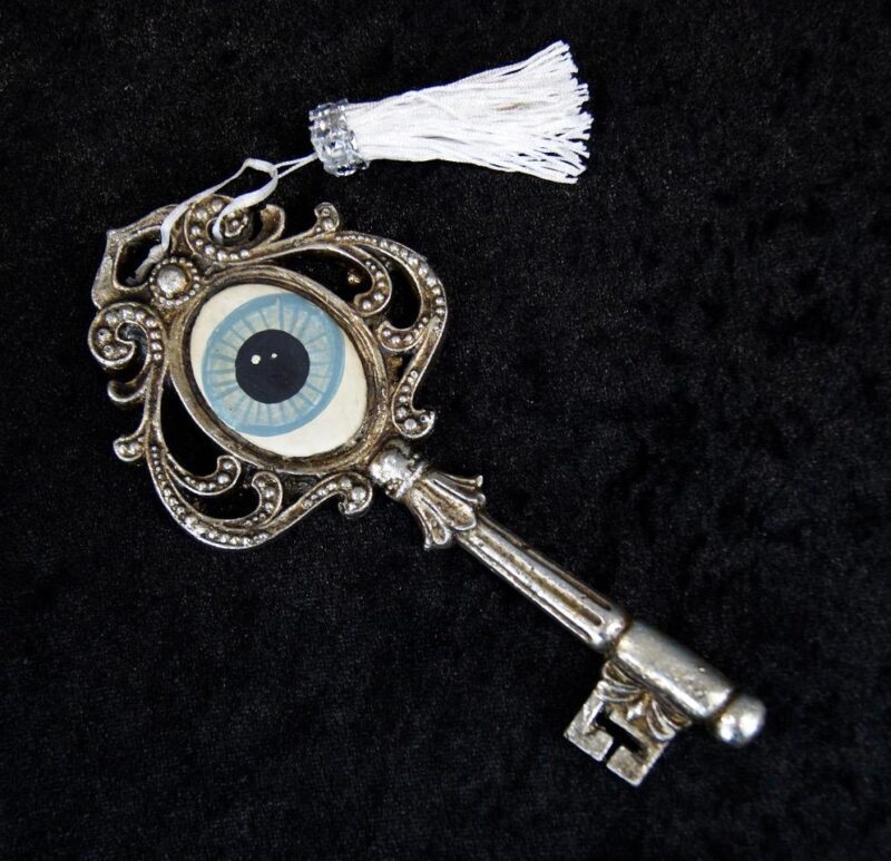 Amaris' key orn silver ant eye design with white tassel