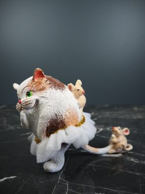 Fat cat playing w/ 2 light brwn mouse in whte fabskirt